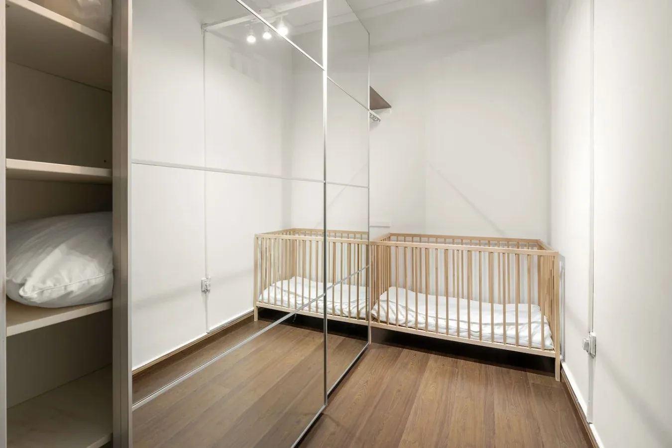 A nursery with a wooden crib and mirrored wardrobe doors.
