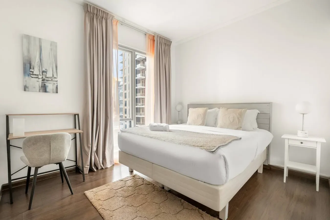Un dormitorio luminoso con una cama bien arreglada junto a una ventana grande.