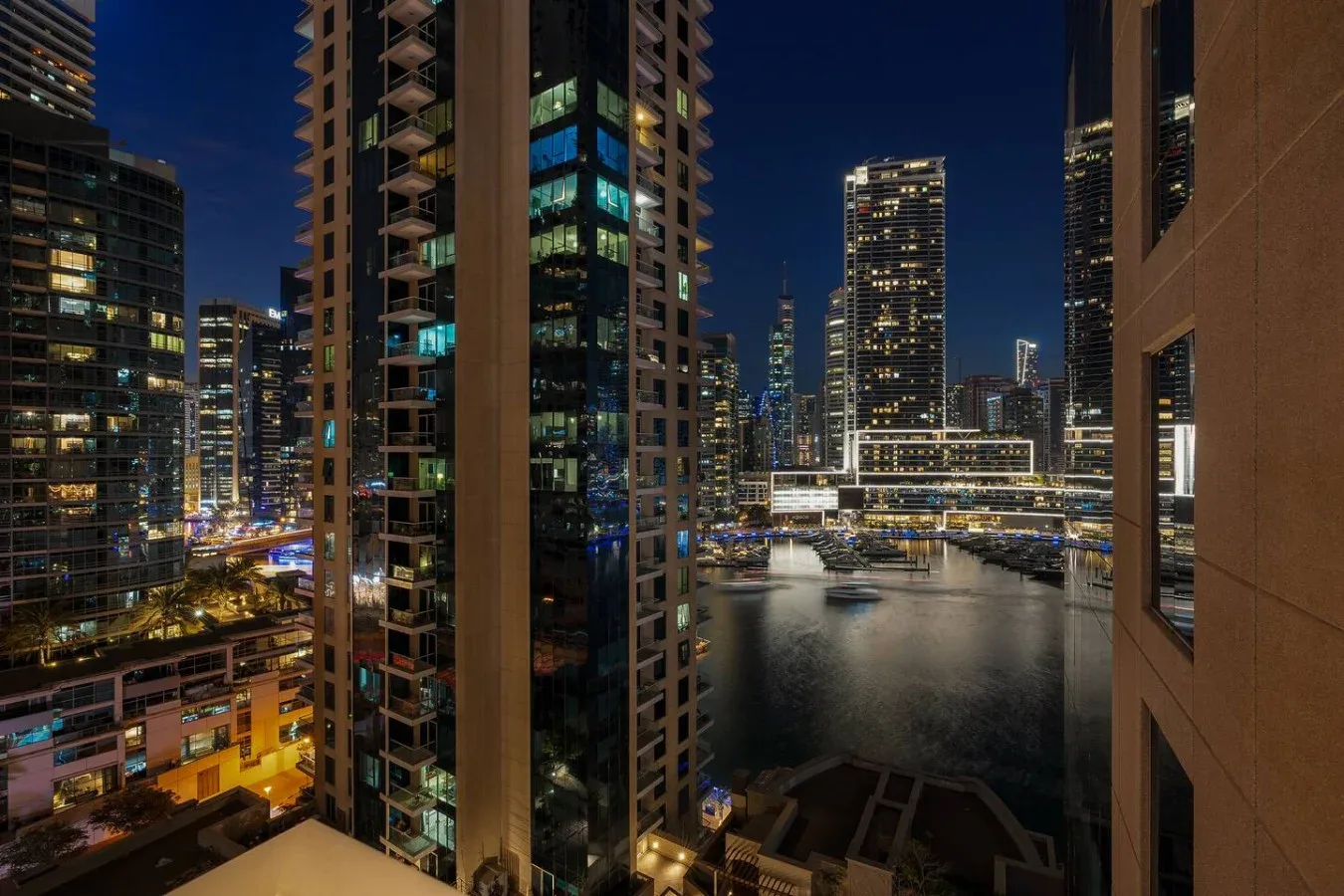 A nighttime city skyline viewed over a waterfront, with illuminated high-rise buildings.