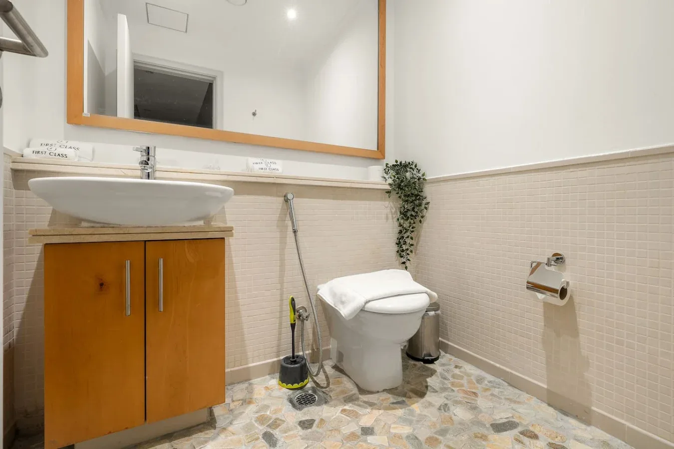 A bathroom with a sink, toilet, and large wall mirror.