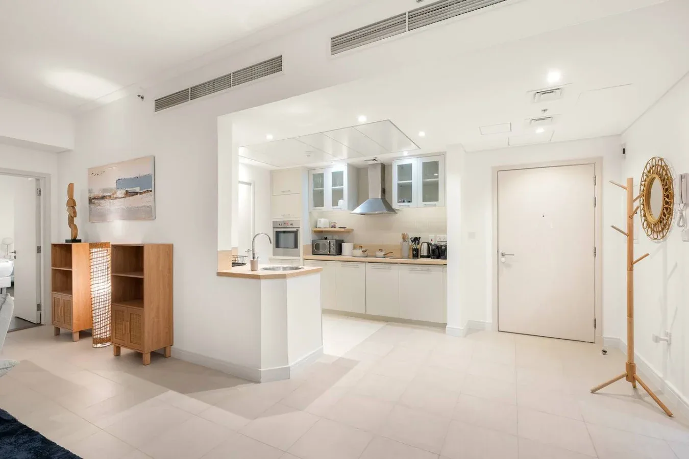 A bright open-plan kitchen and living area with a breakfast counter and wooden shelving.