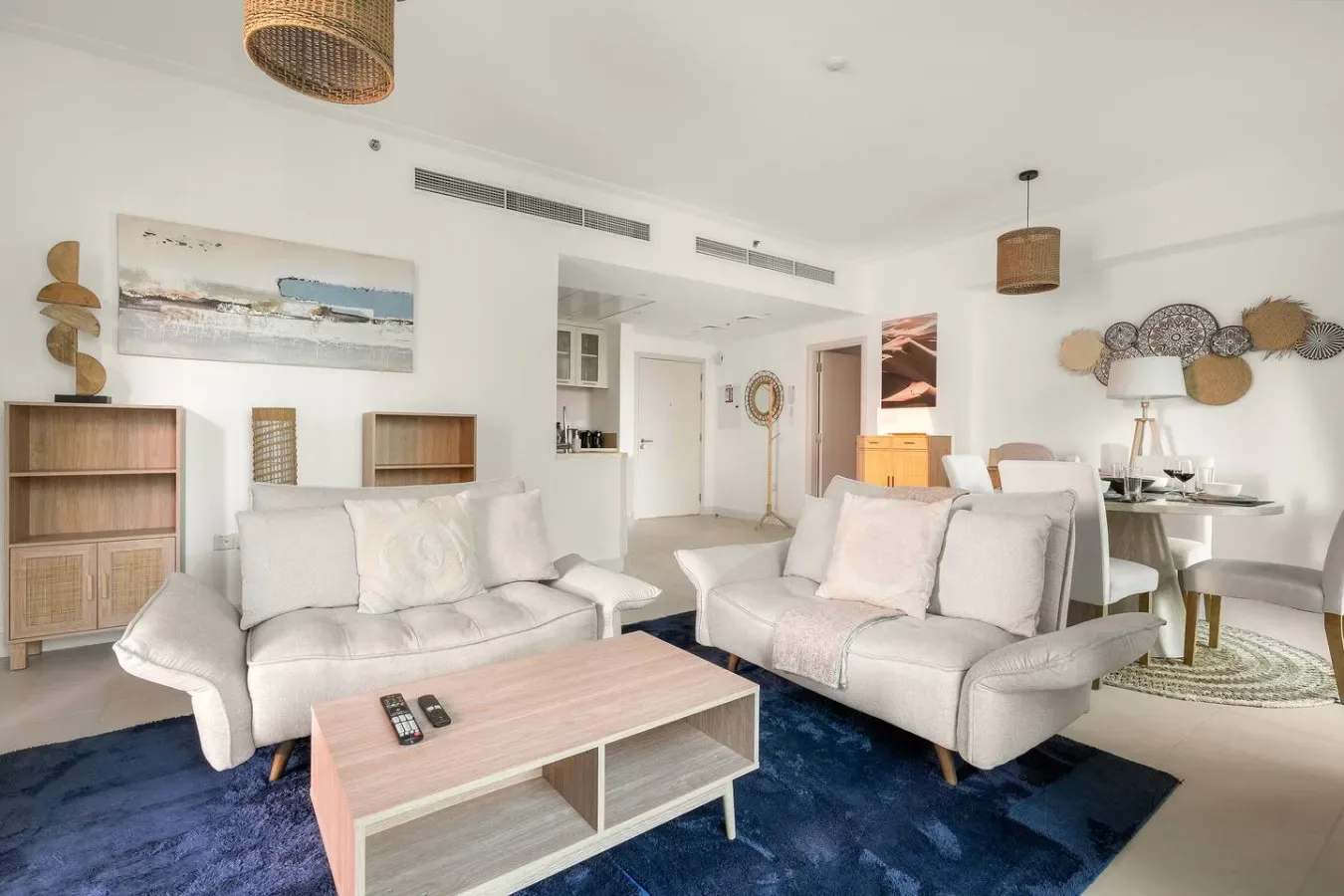 A bright living room with pale seating, a low coffee table, and wall art.