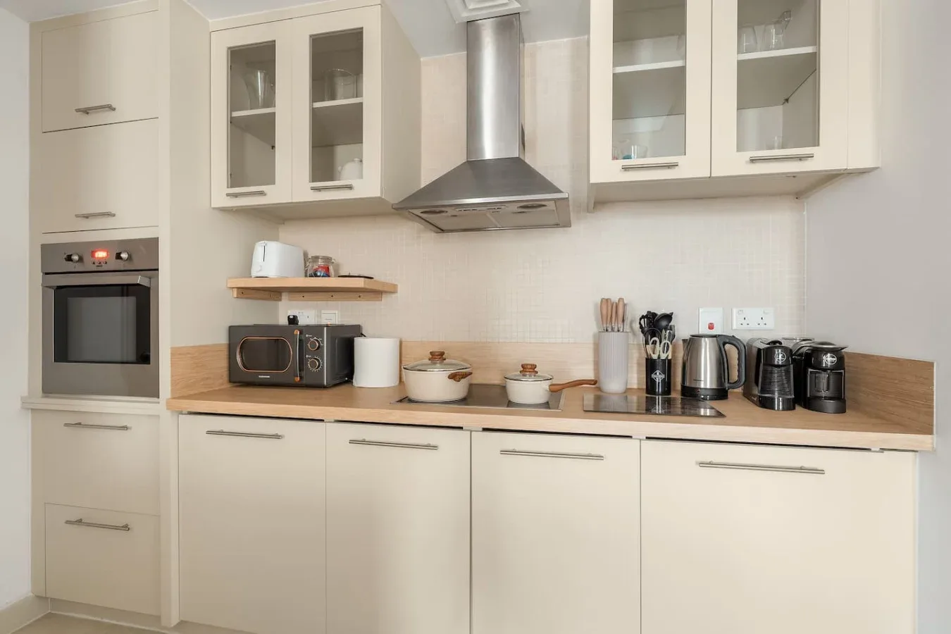 A bright kitchen with cream cabinets, a wooden countertop, and small appliances.