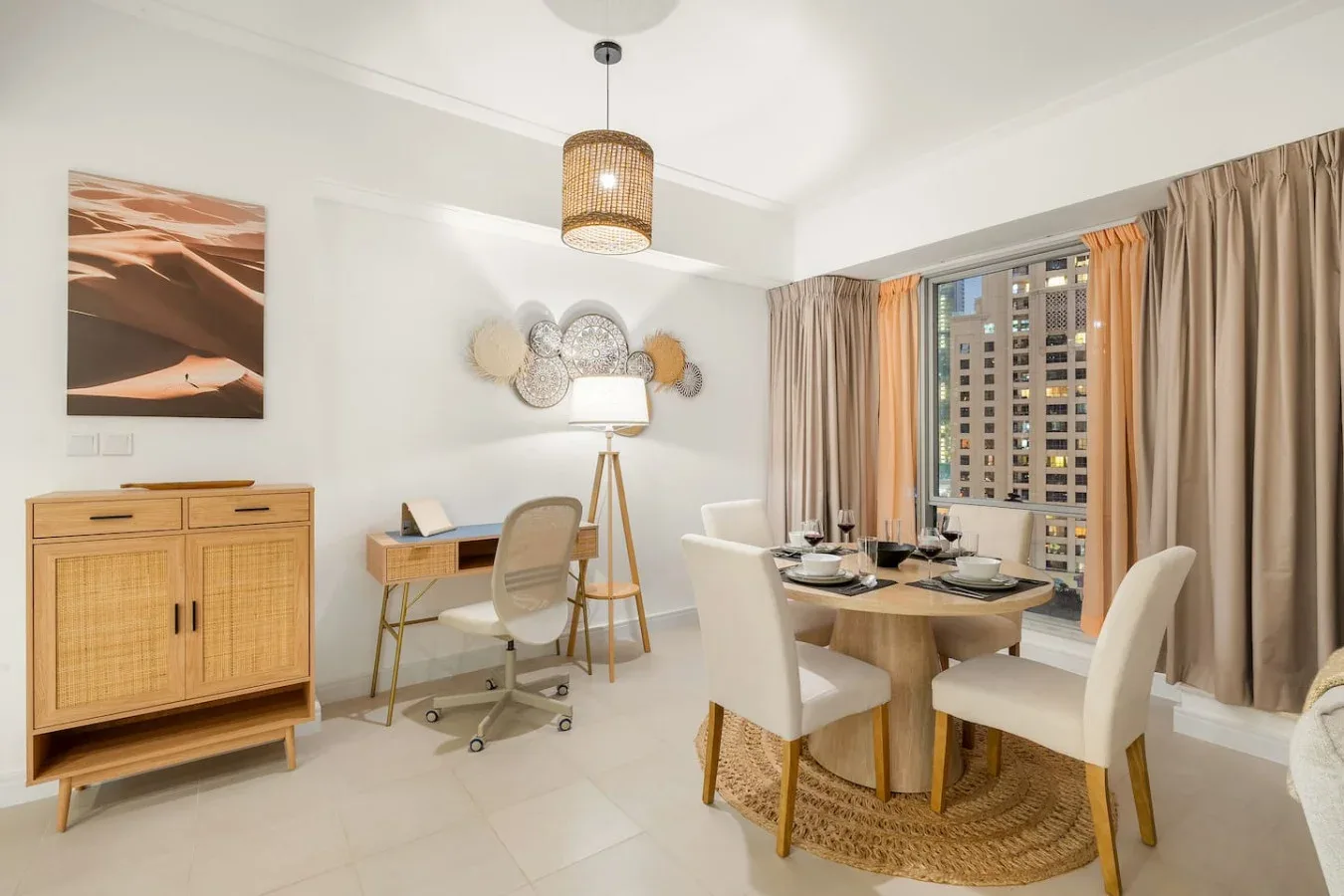 A bright dining area with a set table, chairs, and a desk by the window.
