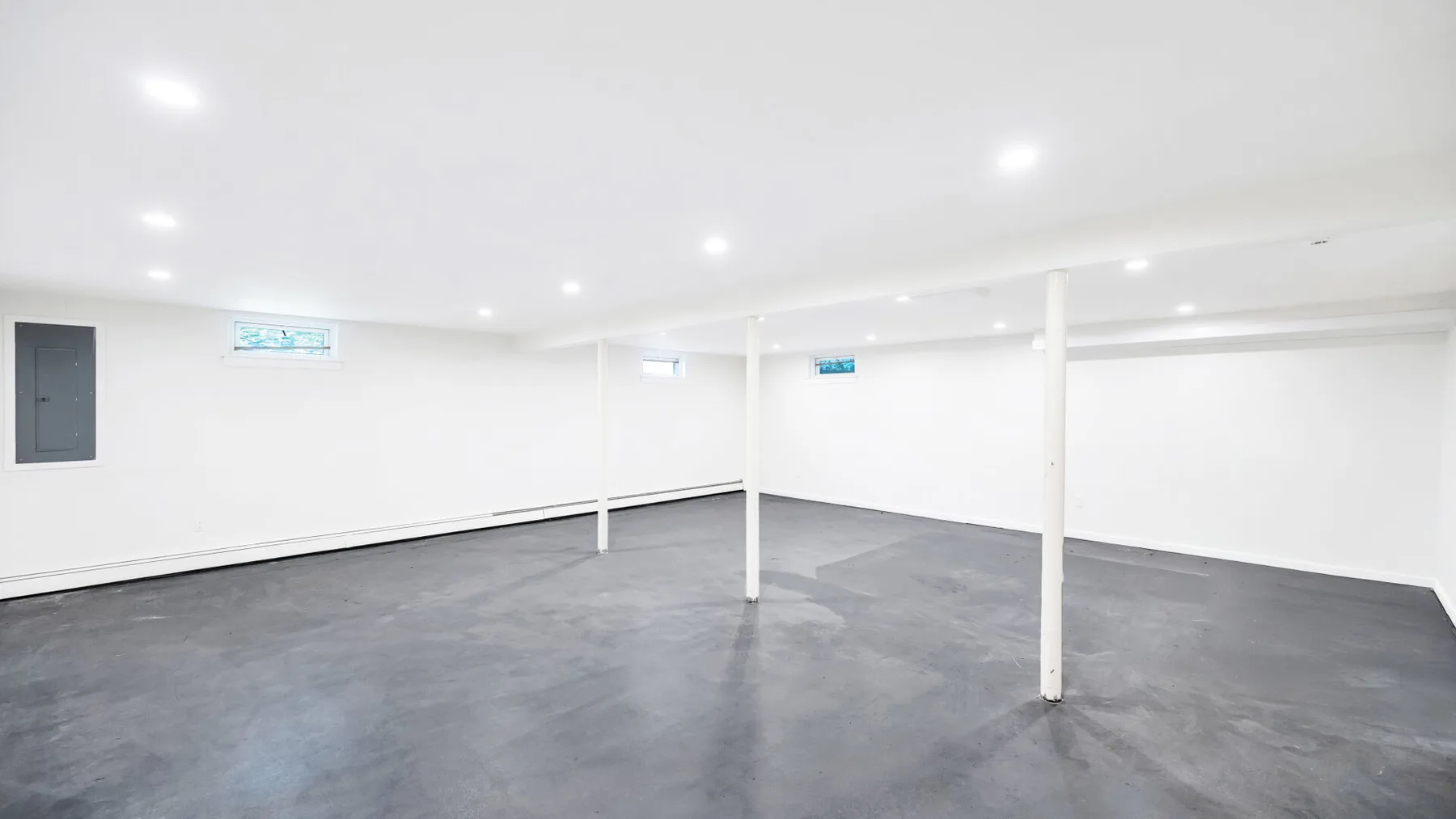 Un espacio interior amplio y abierto, con suelo gris y columnas blancas.