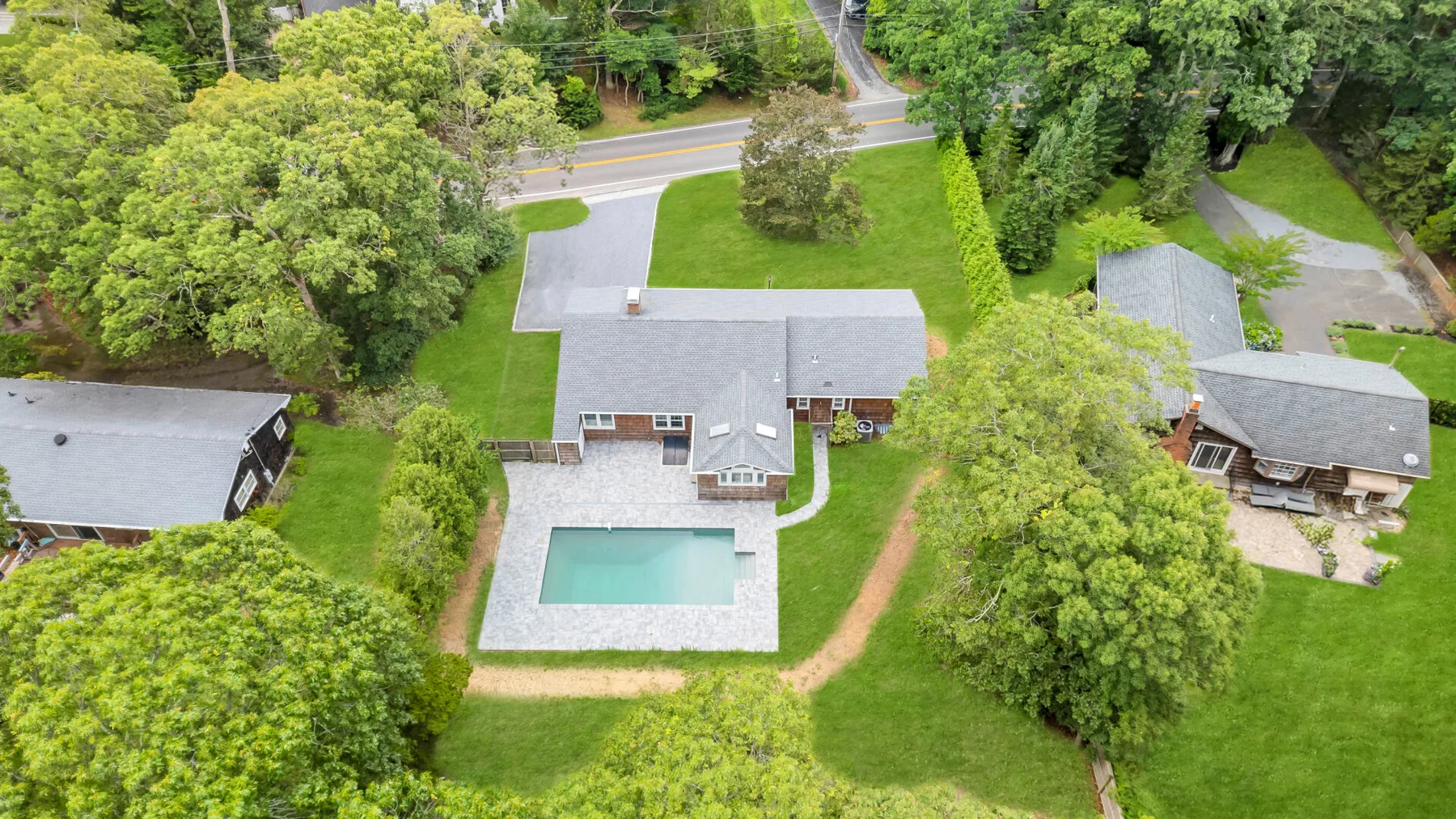 Vista aérea de una casa con piscina y árboles alrededor.