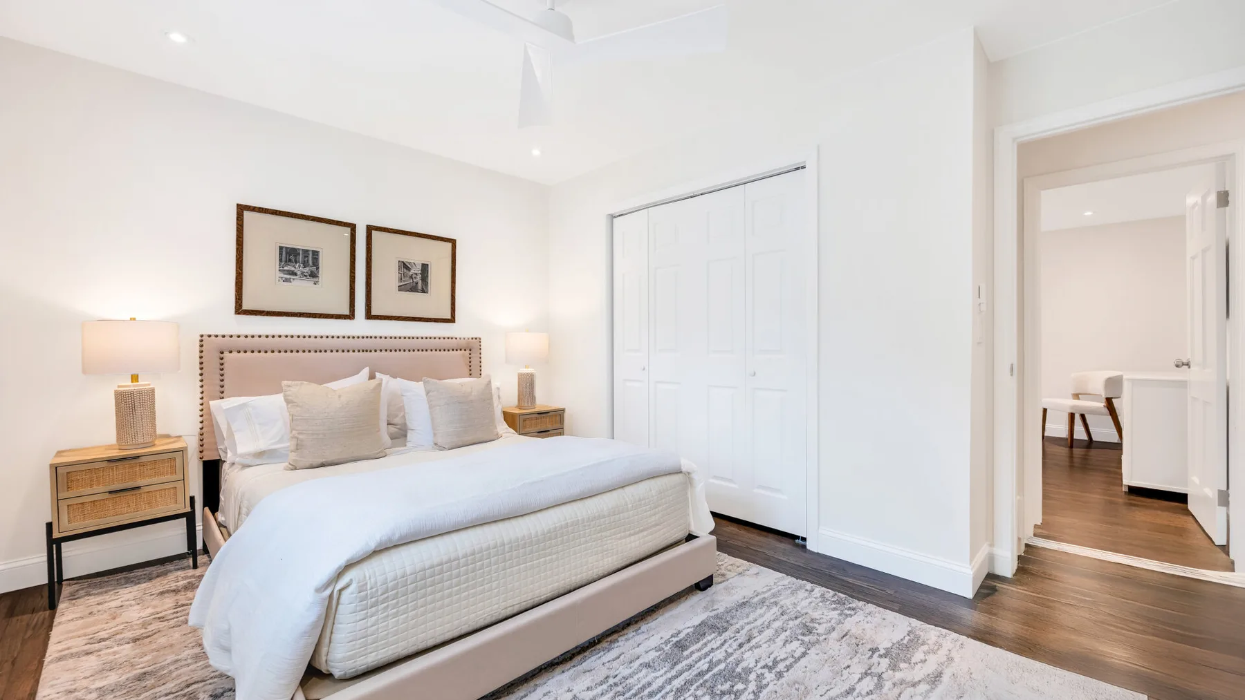 Un dormitorio luminoso con una cama tendida y puertas blancas de armario.