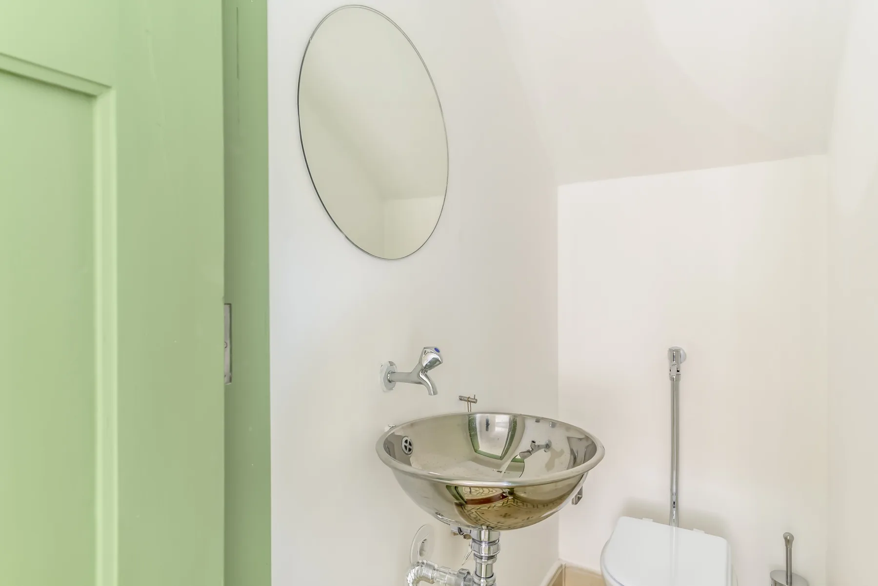 Un lavabo de baño está bajo un espejo redondo.