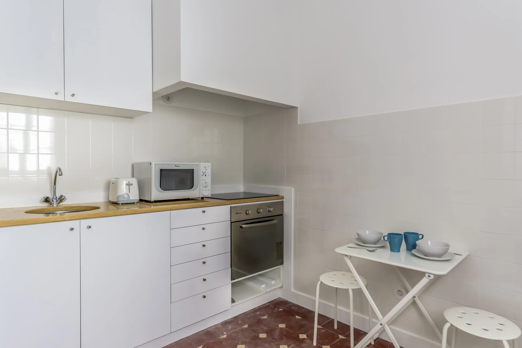 Una cocina luminosa con armarios blancos, una encimera y un horno empotrado.