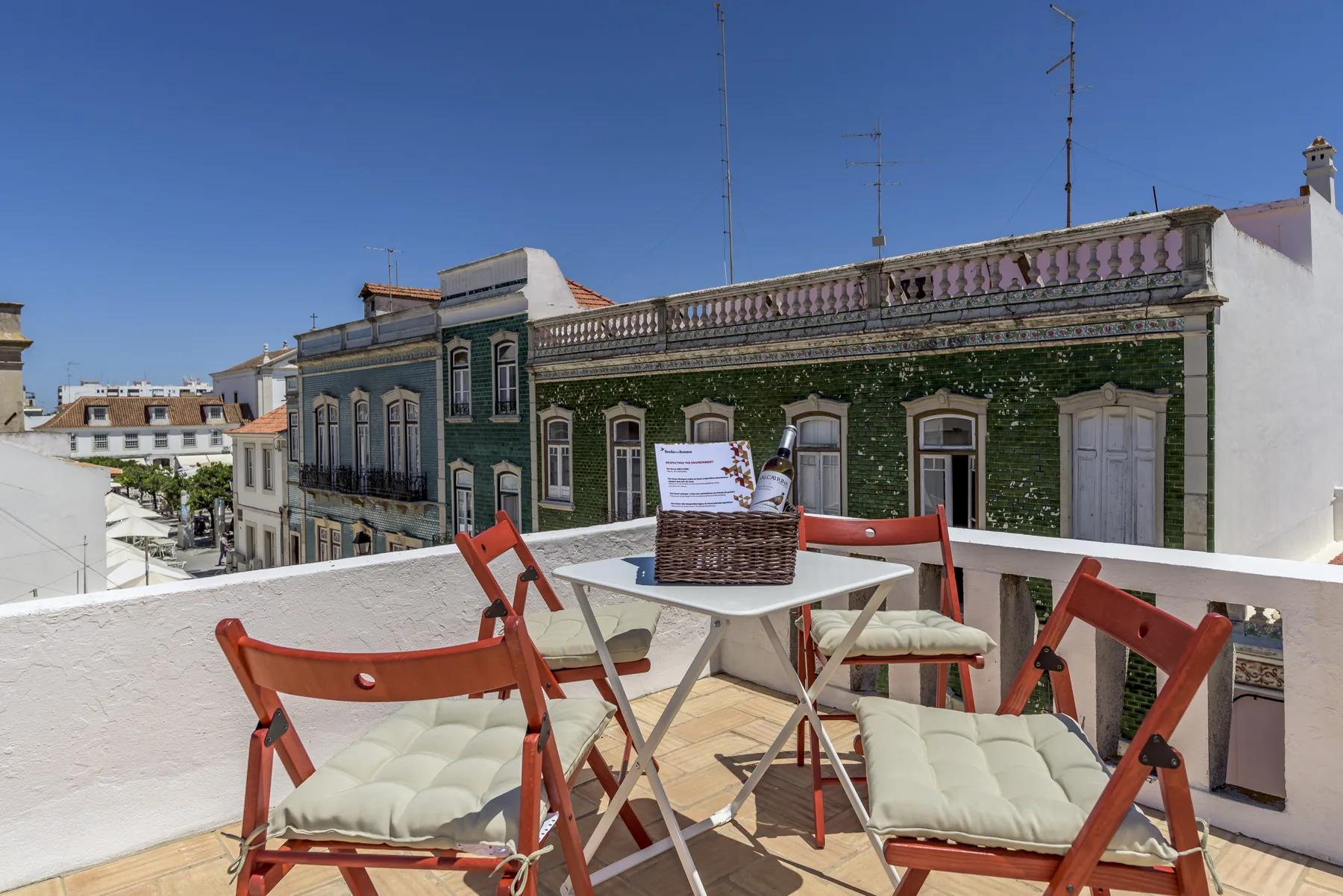 Una terraza en la azotea tiene una mesa y asientos con vistas a edificios cercanos.