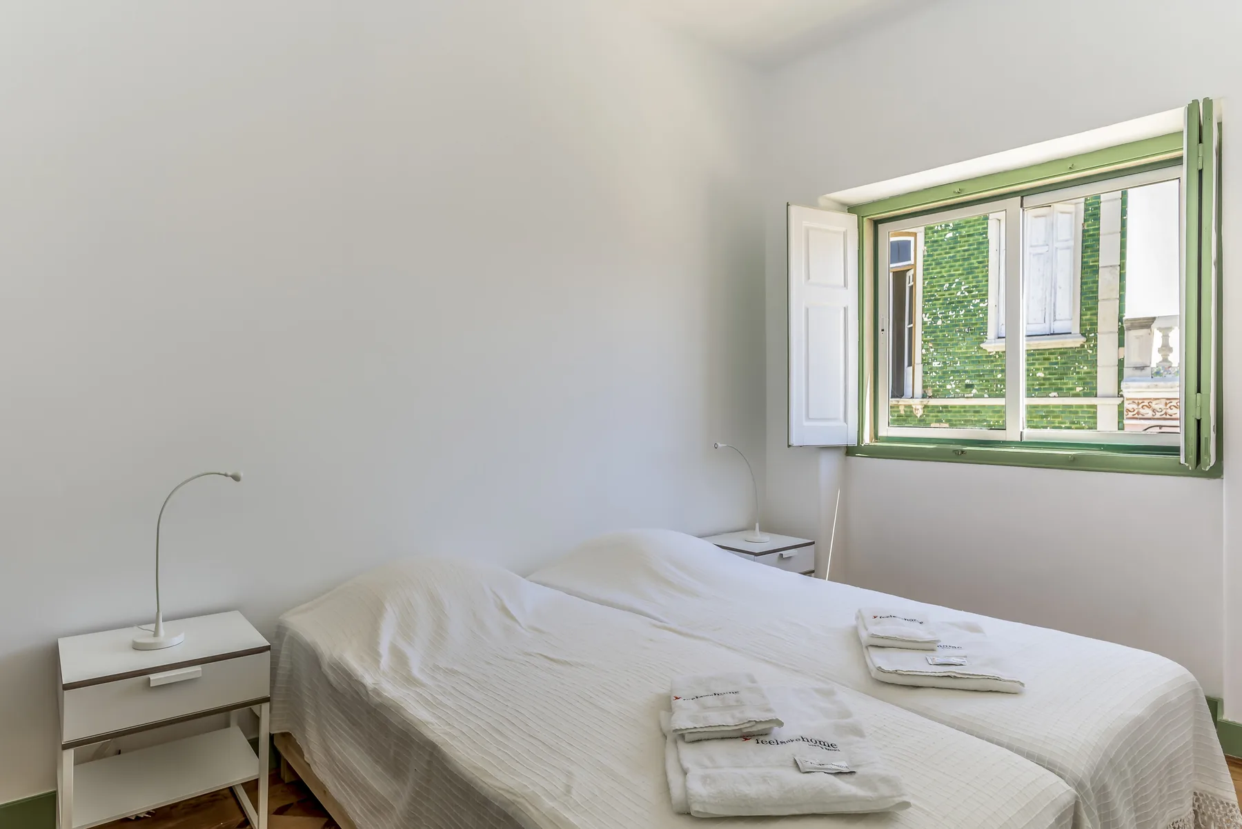 Un dormitorio con una cama, toallas dobladas y una ventana abierta.