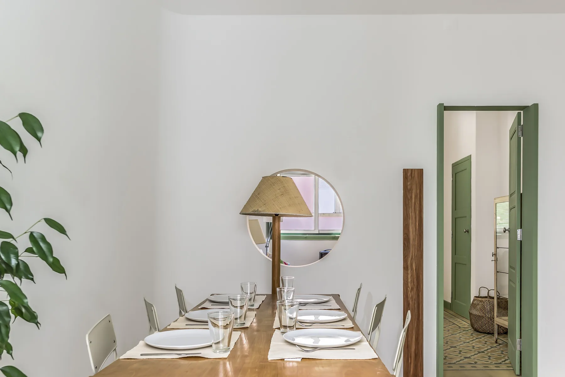 Un comedor con una mesa de madera puesta bajo un espejo redondo.