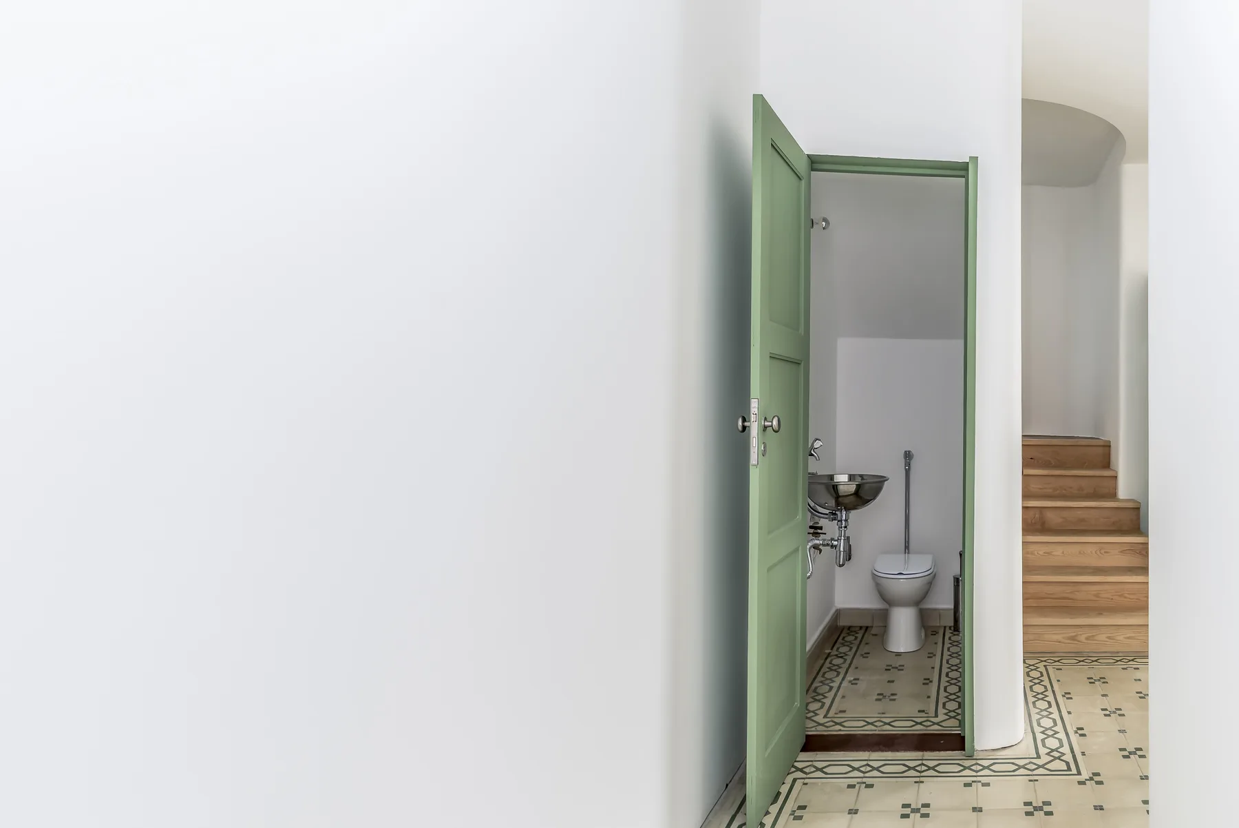 Un baño con lavabo e inodoro junto a una escalera.