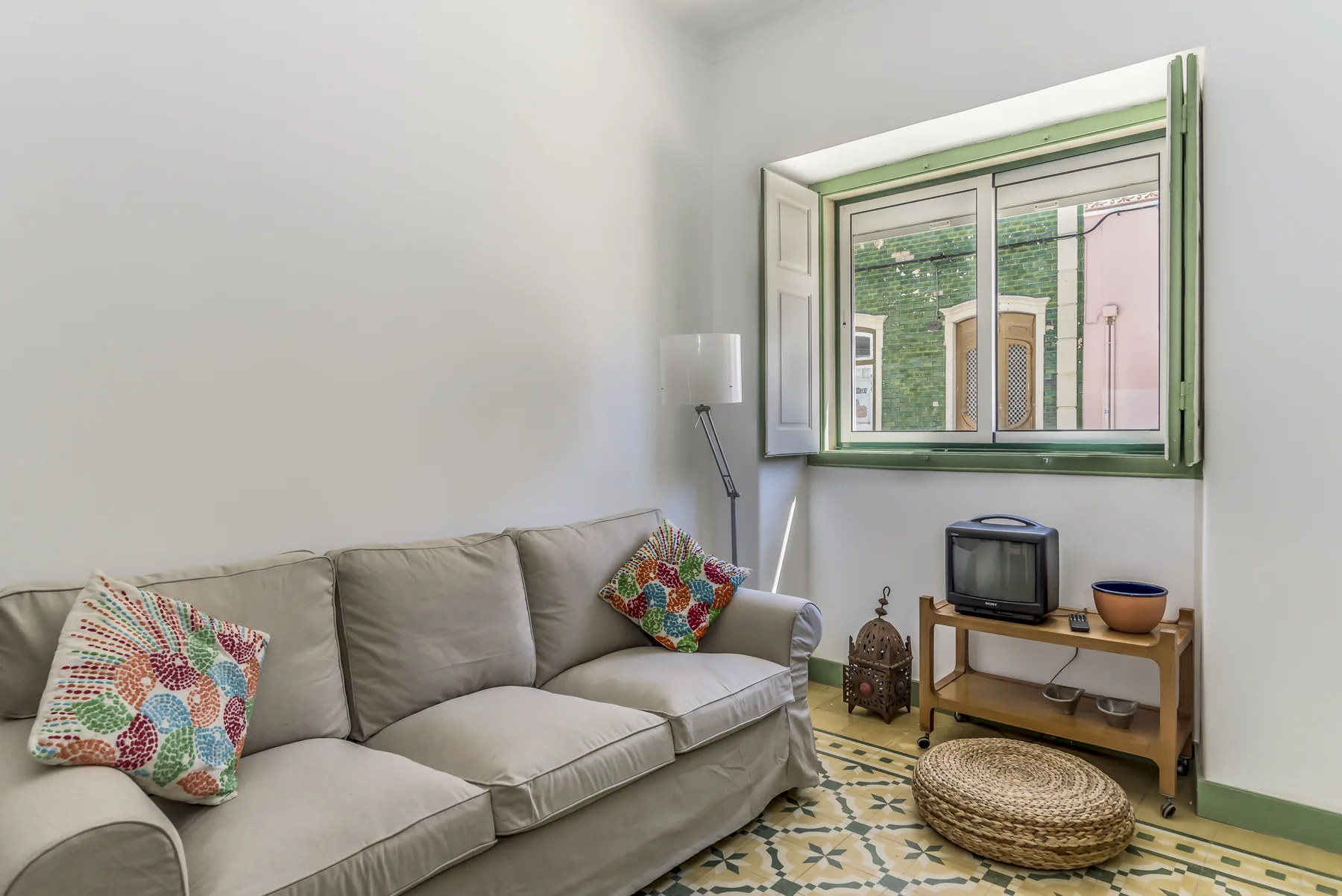 Una sala de estar con asientos, una ventana y baldosas estampadas.