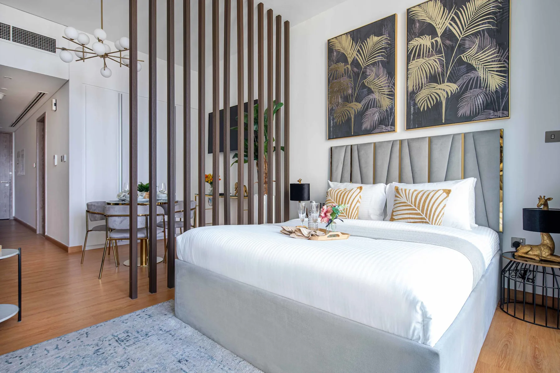 A bedroom with a neatly made bed and a wooden slat divider.