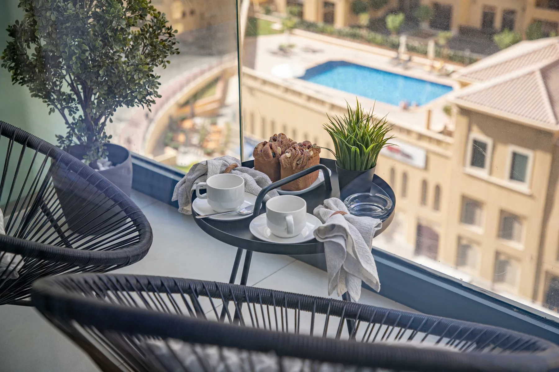 A balcony seating area with a small table set beside a large window.