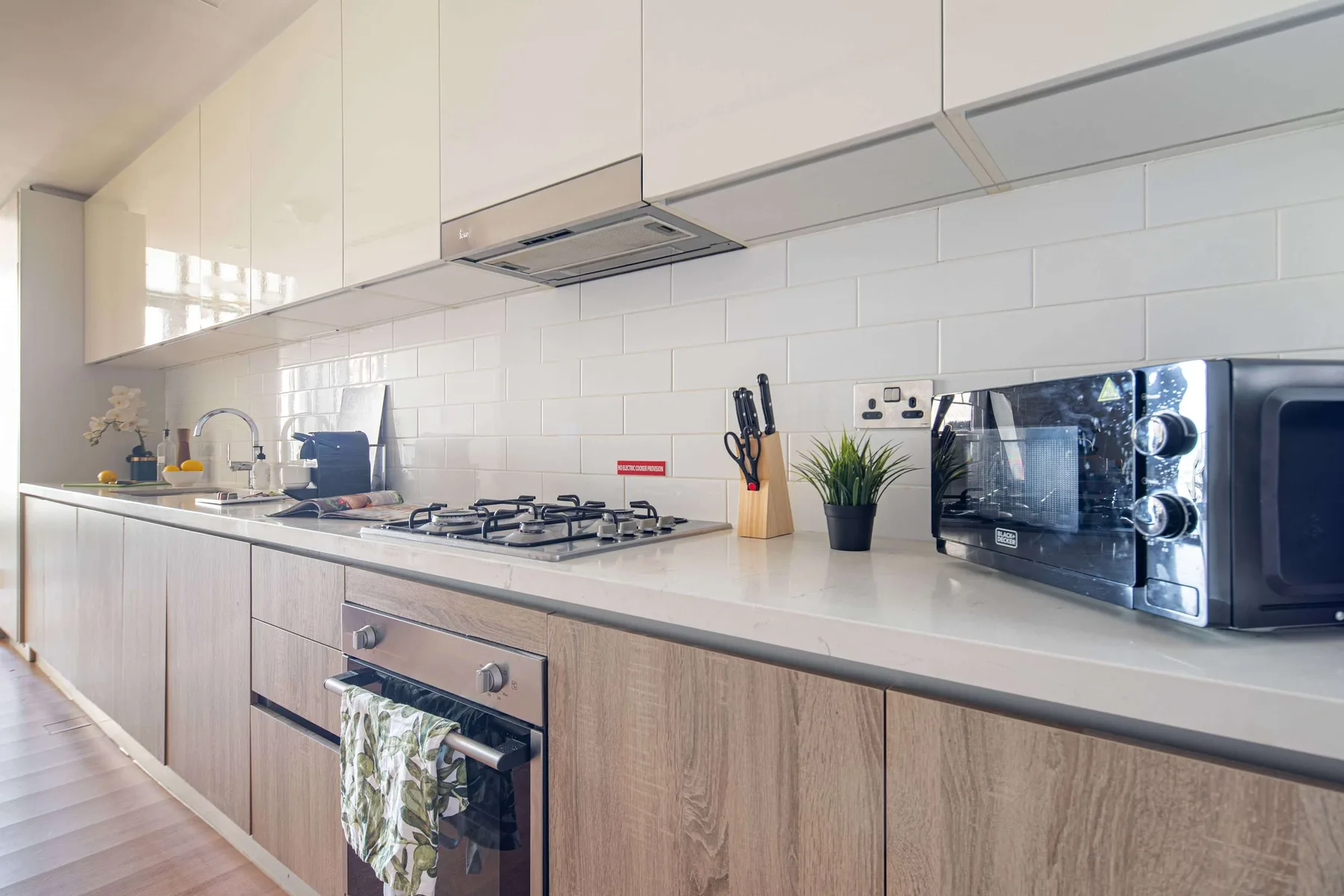 A modern kitchen with a long countertop, cooktop, and small appliances.