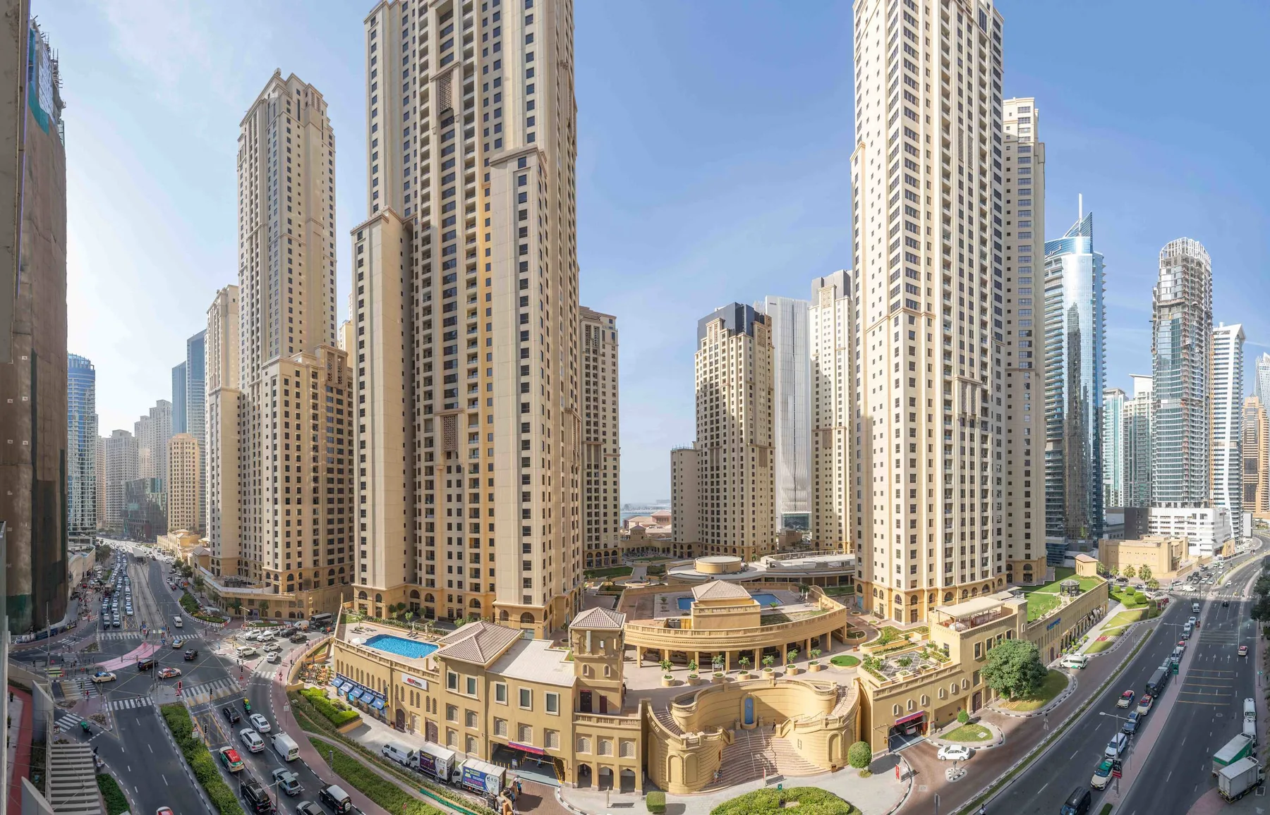 A city skyline of tall buildings overlooks busy roads and a low-rise complex.