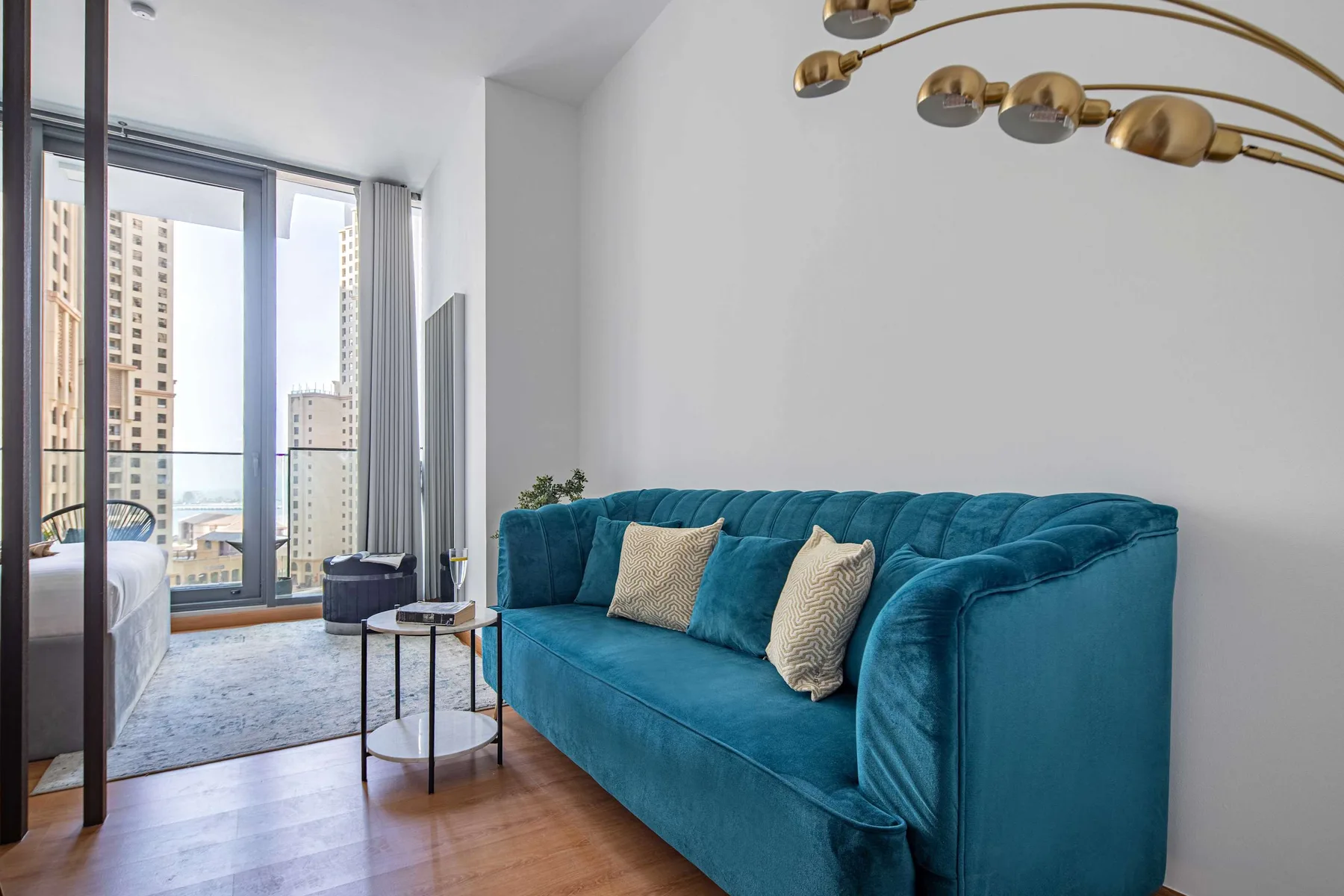 A living room with teal seating, a coffee table, and large windows.
