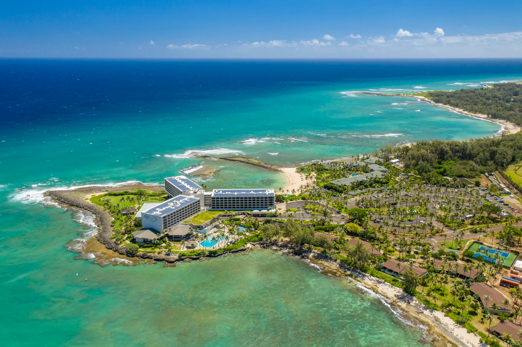 Aerial view of a coastal resort beside turquoise water and a sandy beach.