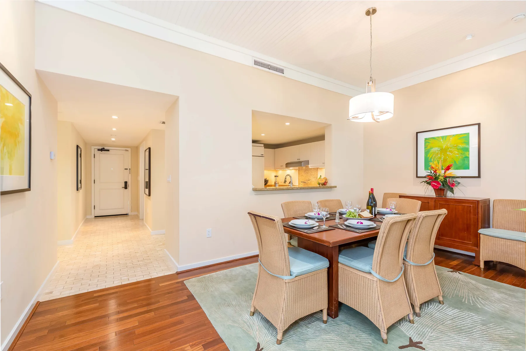 A dining area with a wooden table, cushioned seating, and framed wall art.
