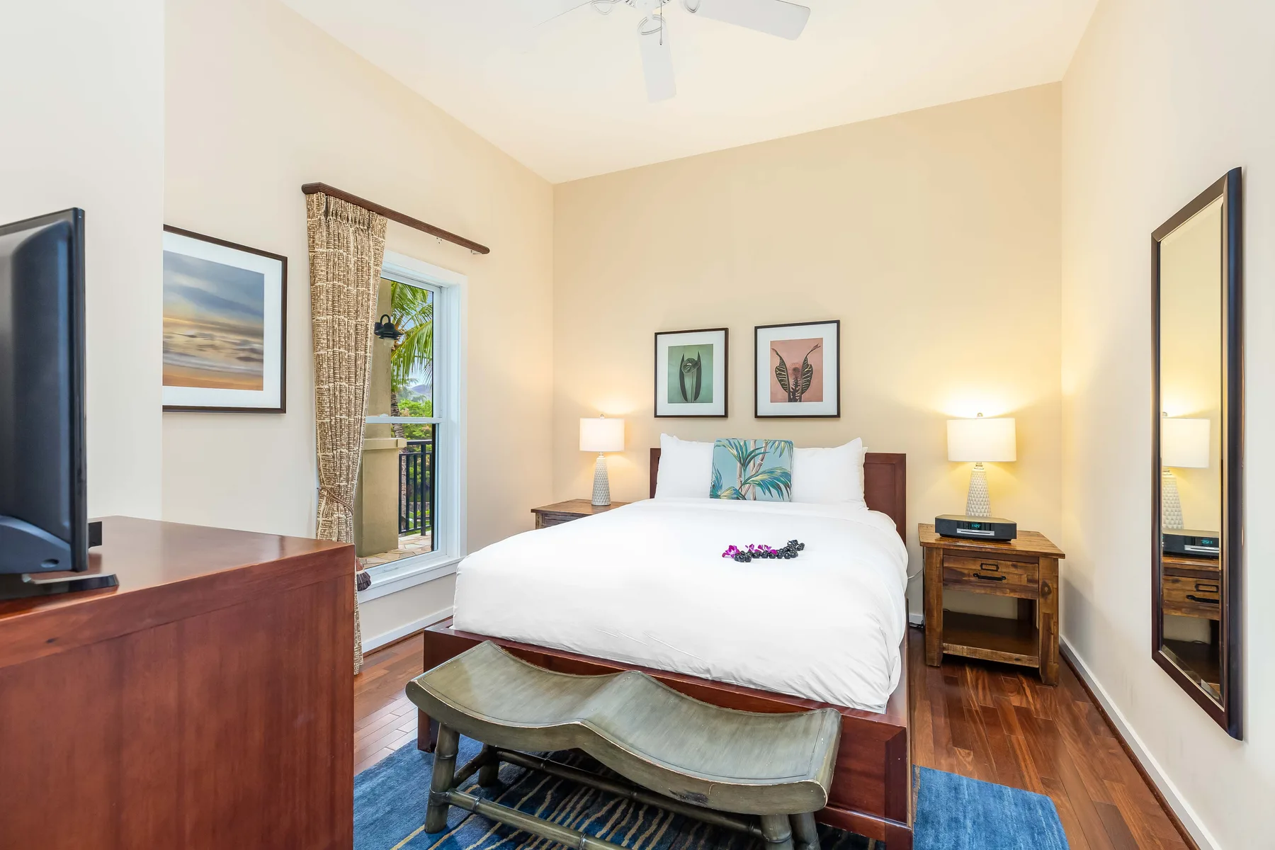 A bright bedroom with a bed, bedside lamps, and a window.