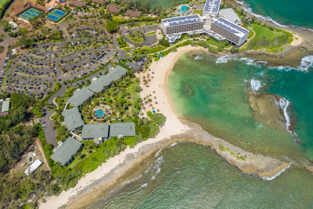 An aerial view of a coastal resort beside a curved sandy beach and turquoise water.