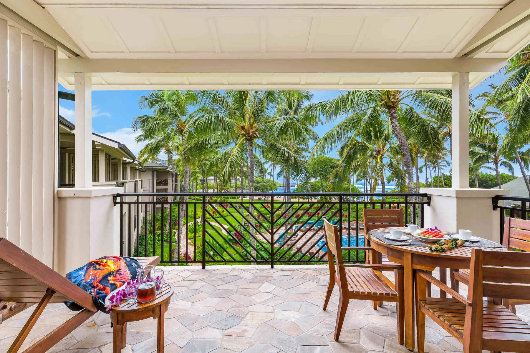 A covered outdoor dining area overlooks palm trees and greenery.