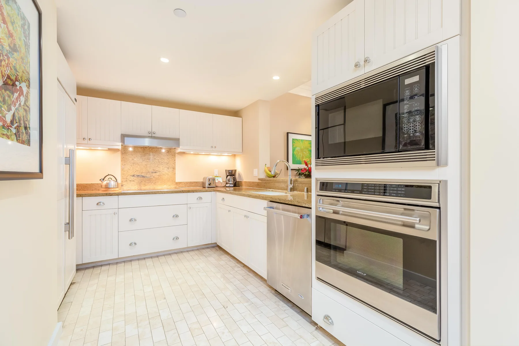 A bright kitchen with white cabinets, a tiled floor, and built-in appliances.