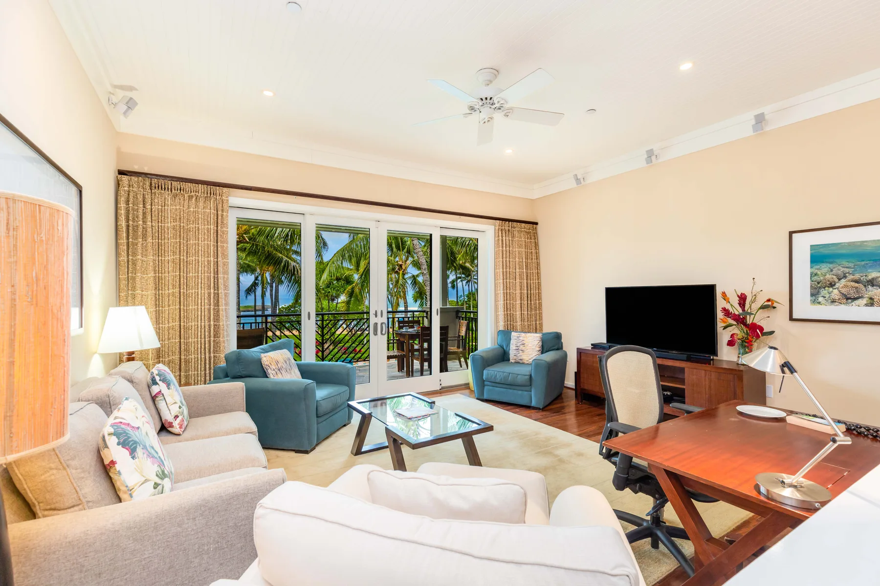 A bright living room with seating, a television, and glass doors opening to a balcony.
