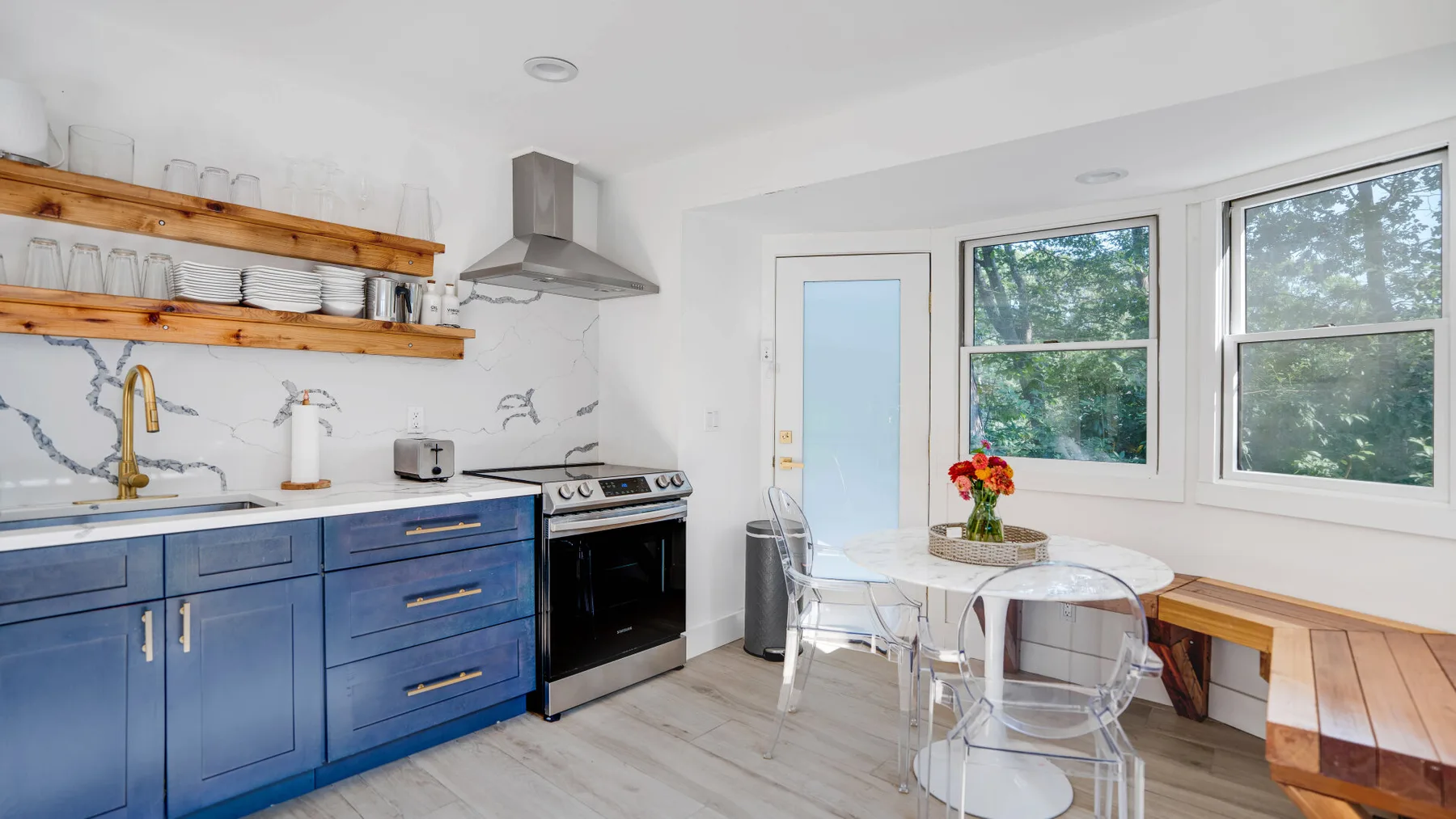 Una cocina luminosa con gabinetes azules, una mesa de comedor y ventanas grandes.