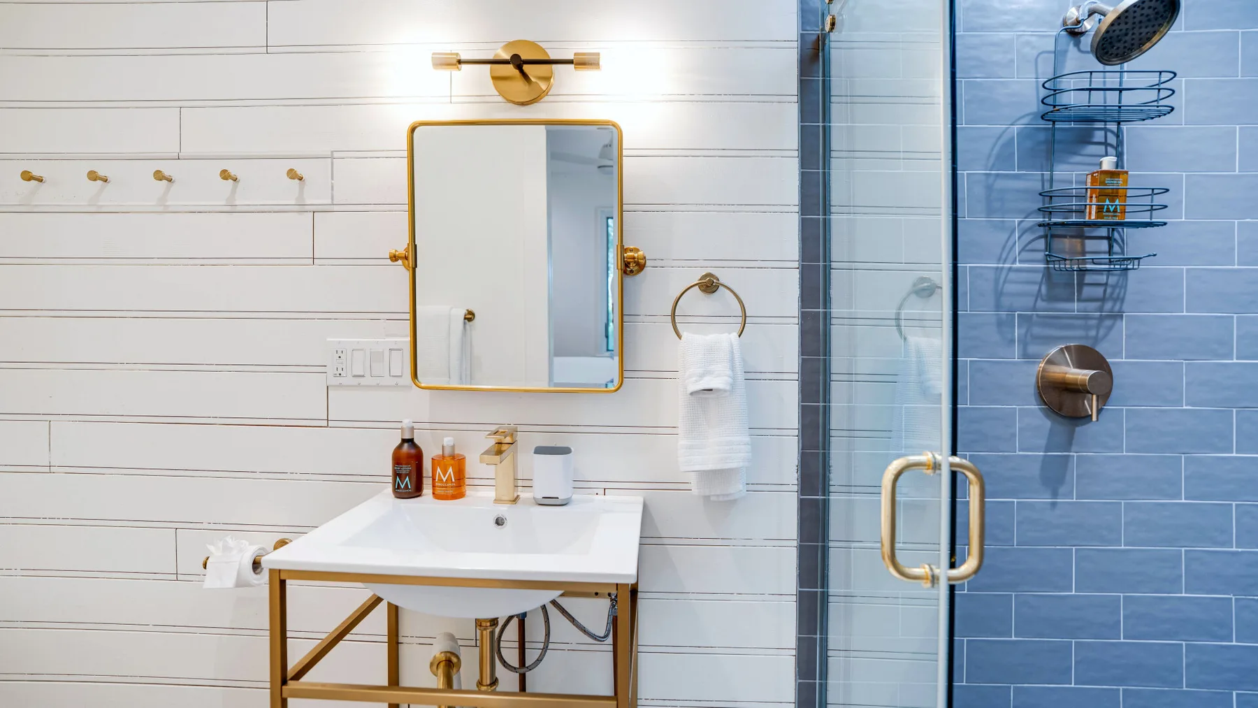 Un baño luminoso con lavabo, espejo de pared y ducha de cristal.