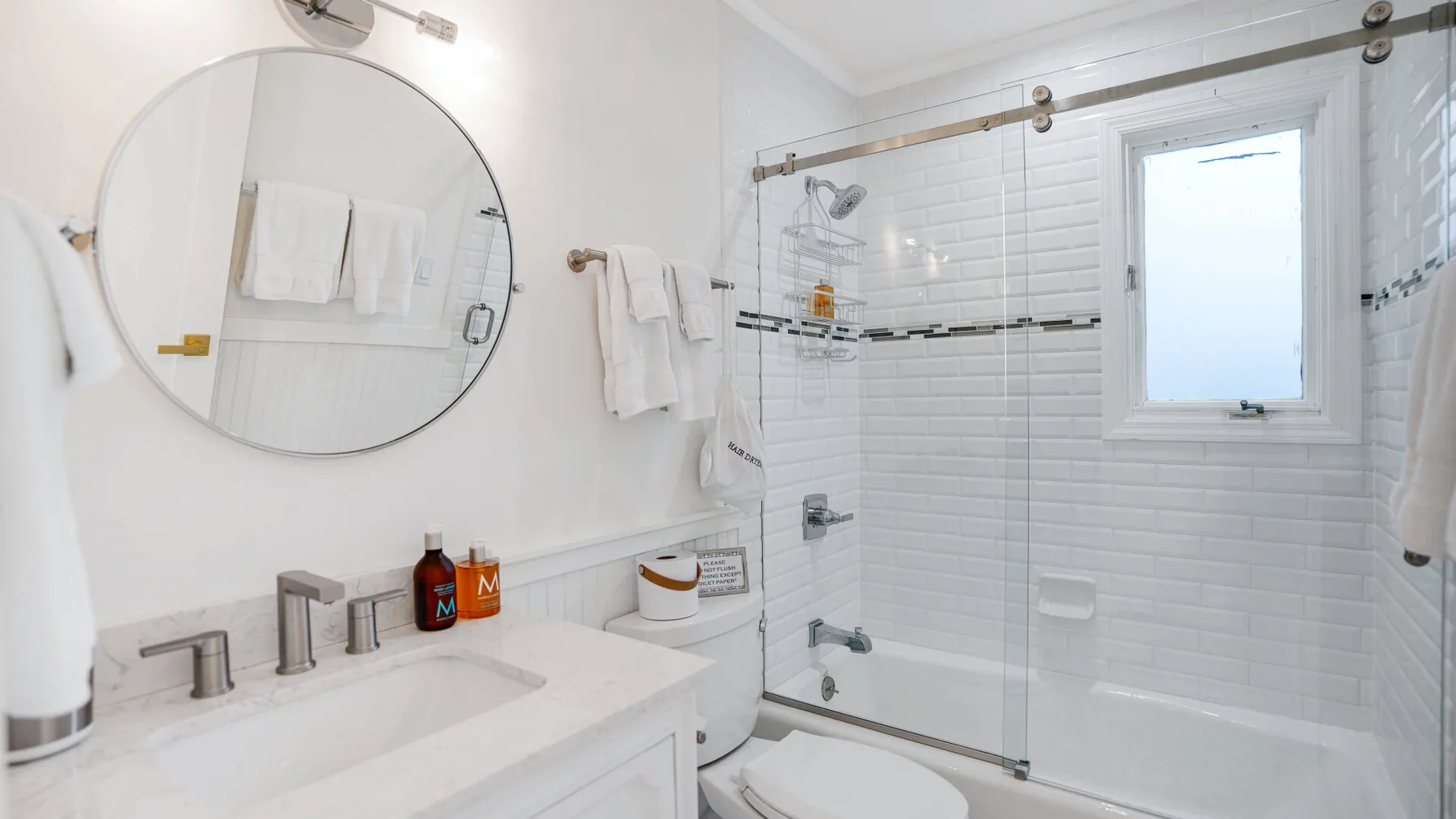 Un baño luminoso con ducha de vidrio y un lavabo amplio.