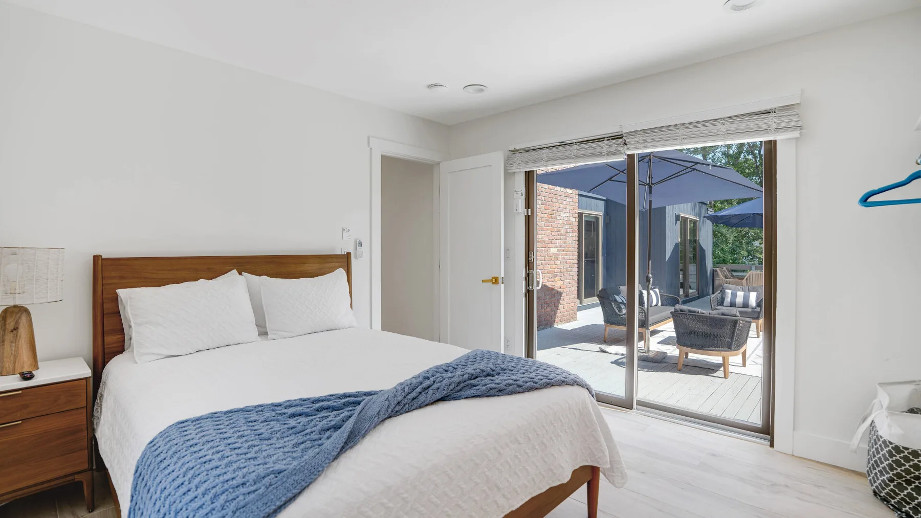 Un dormitorio luminoso con una cama bien tendida junto a puertas corredizas de vidrio que dan a un patio.