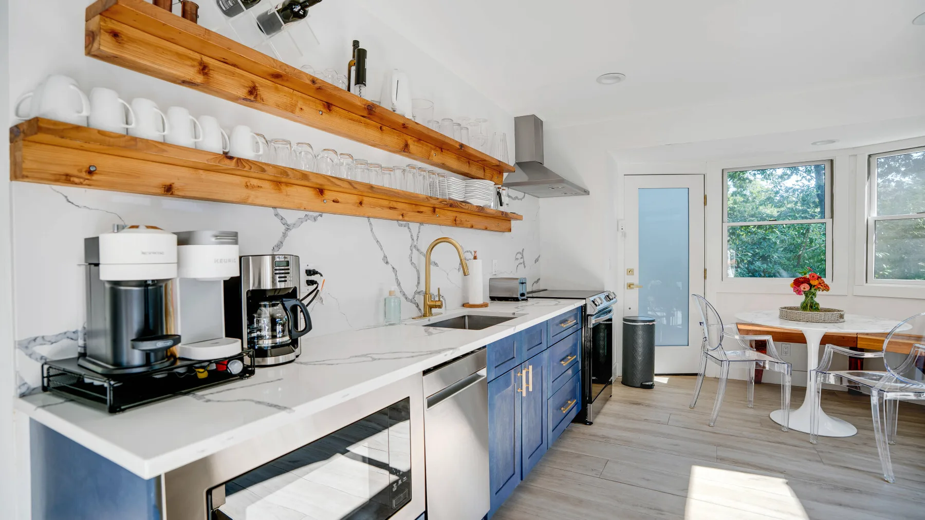 Una cocina luminosa con una encimera larga y una pequeña zona de comedor junto a las ventanas.