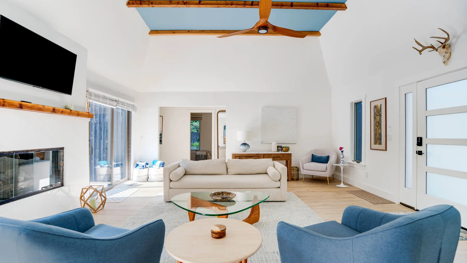 Una sala luminosa con asientos, una mesa de centro de vidrio y ventanales.