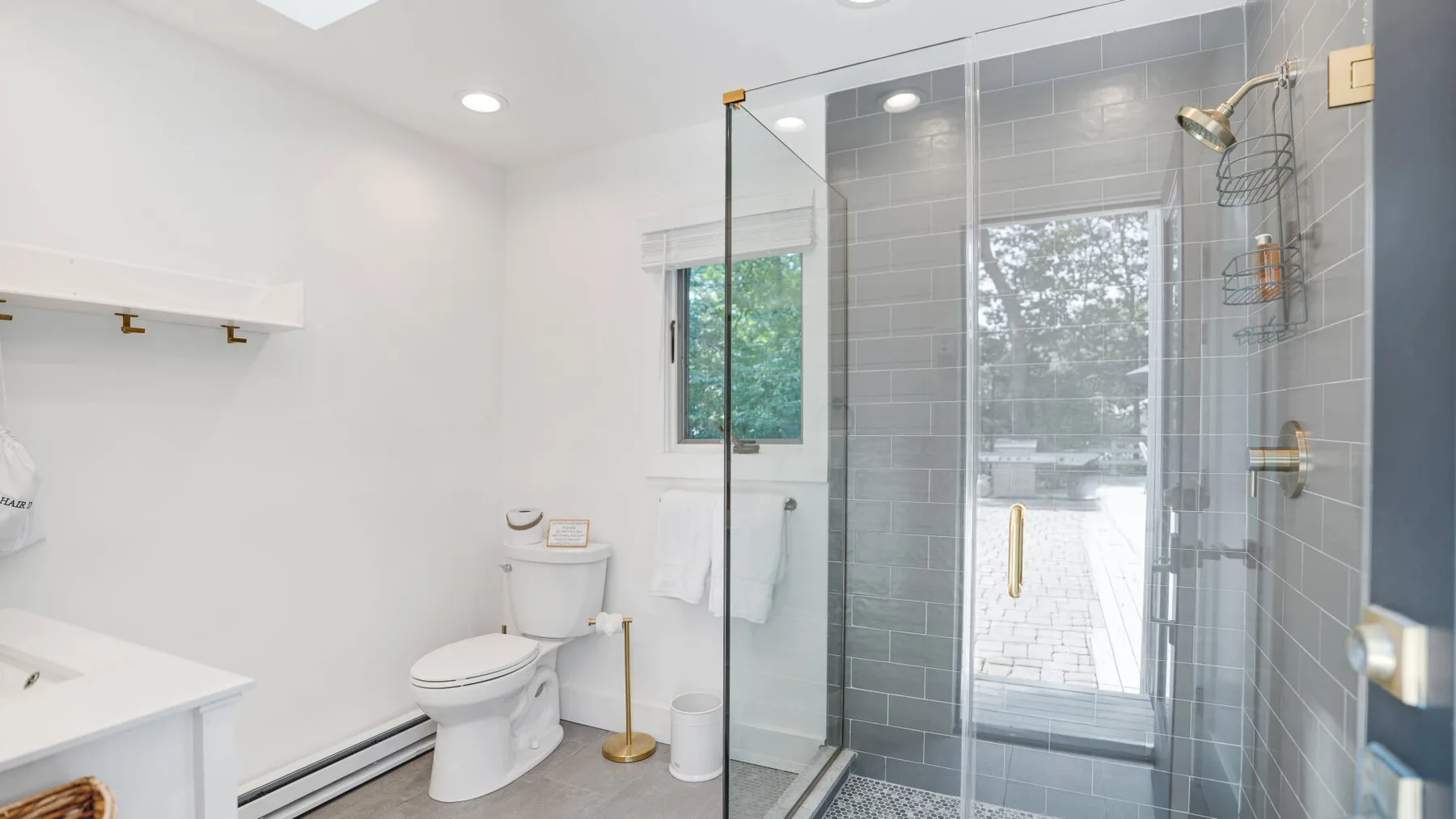 Un baño luminoso con inodoro, lavabo y ducha de vidrio.