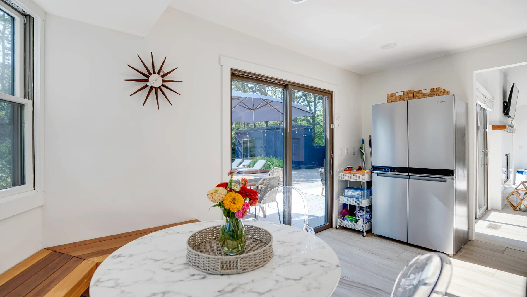 Una cocina luminosa con comedor y una mesa junto a puertas corredizas de vidrio.