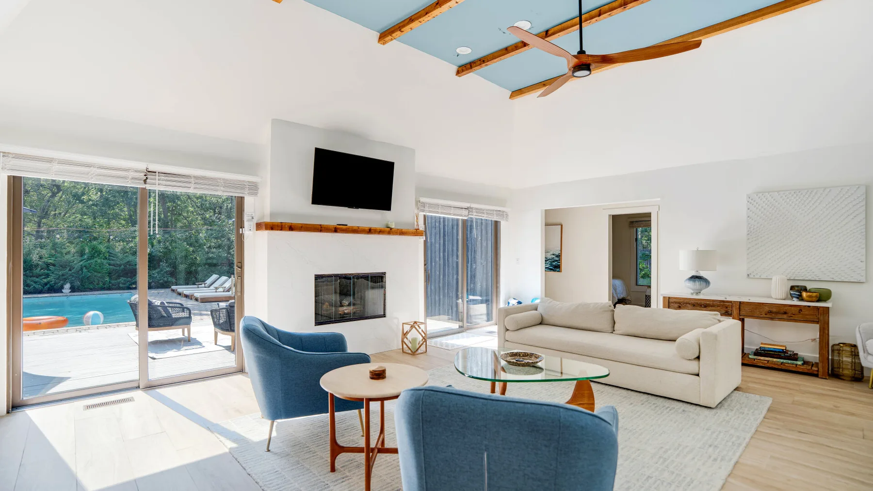 Una sala luminosa con asientos azules, una chimenea y puertas corredizas de vidrio.