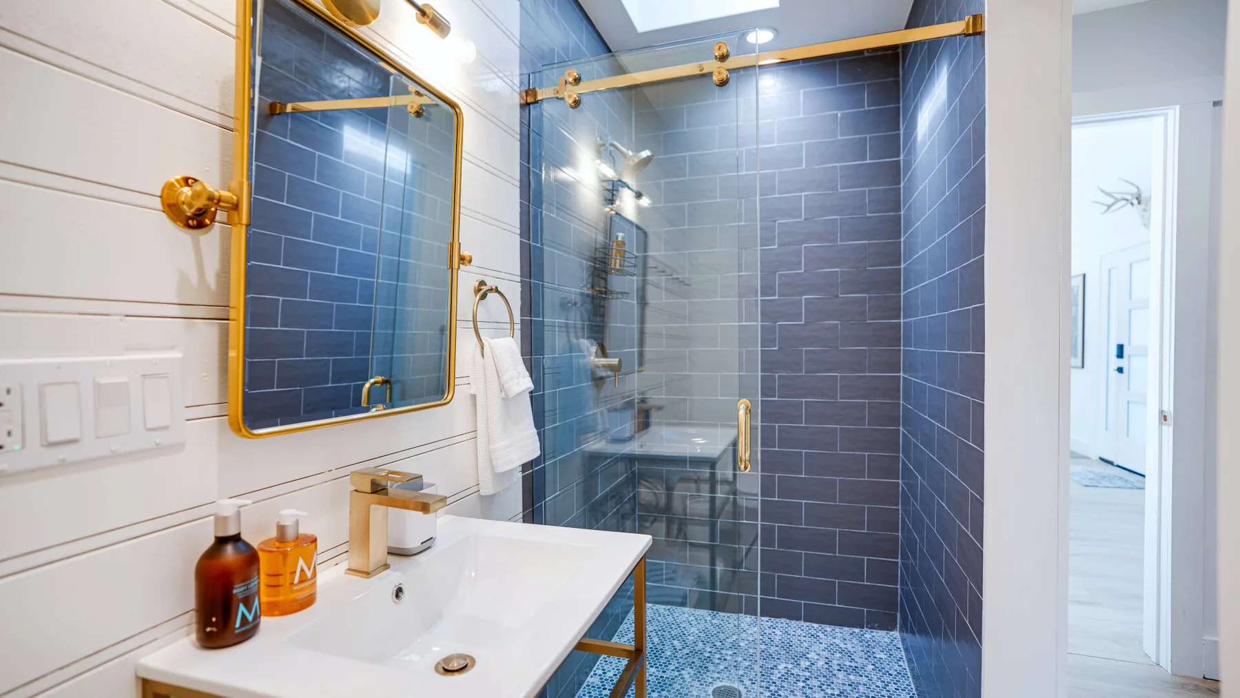 Un baño con azulejos, lavabo y ducha de cristal.