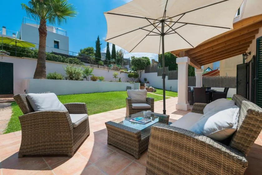 A sunny patio with outdoor seating, a table, and a large umbrella.