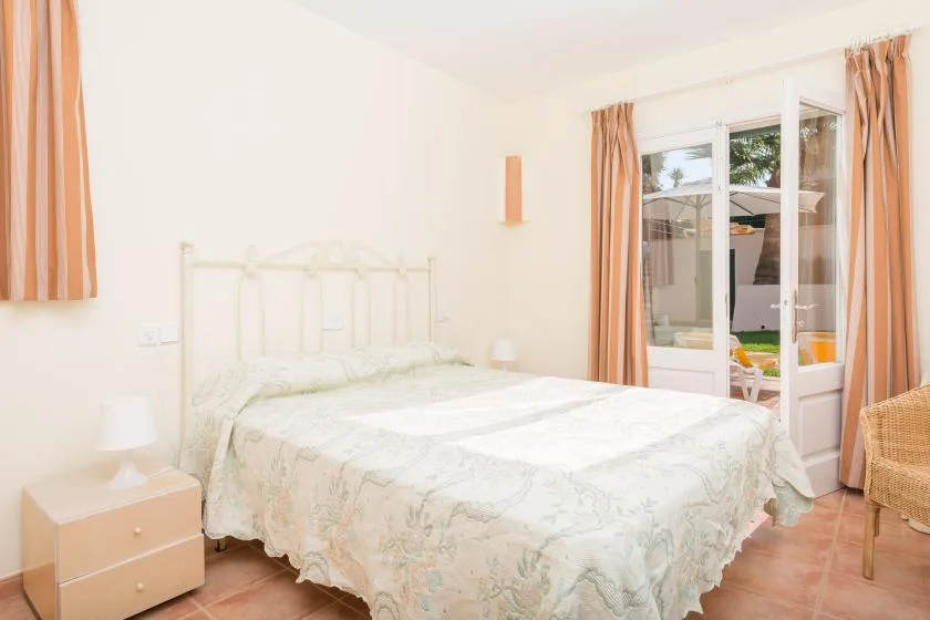 A bright bedroom with a double bed beside glass doors opening onto a patio.