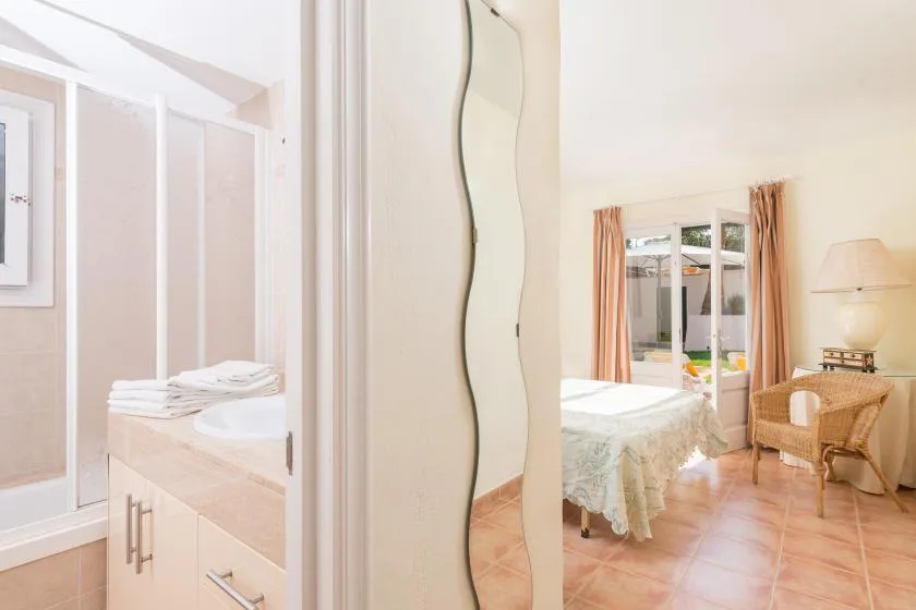A bedroom with a bed, a wicker chair, and a mirrored wardrobe.