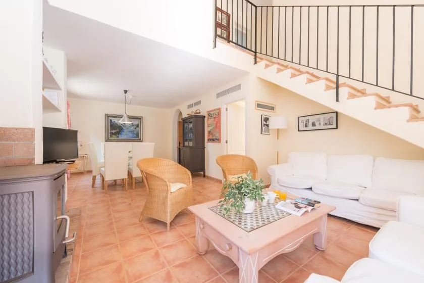 A bright living room with seating, a coffee table, and a staircase.