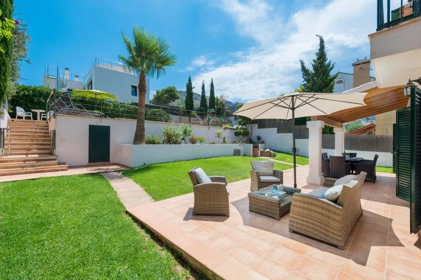 A sunny garden patio with outdoor seating and a large umbrella.