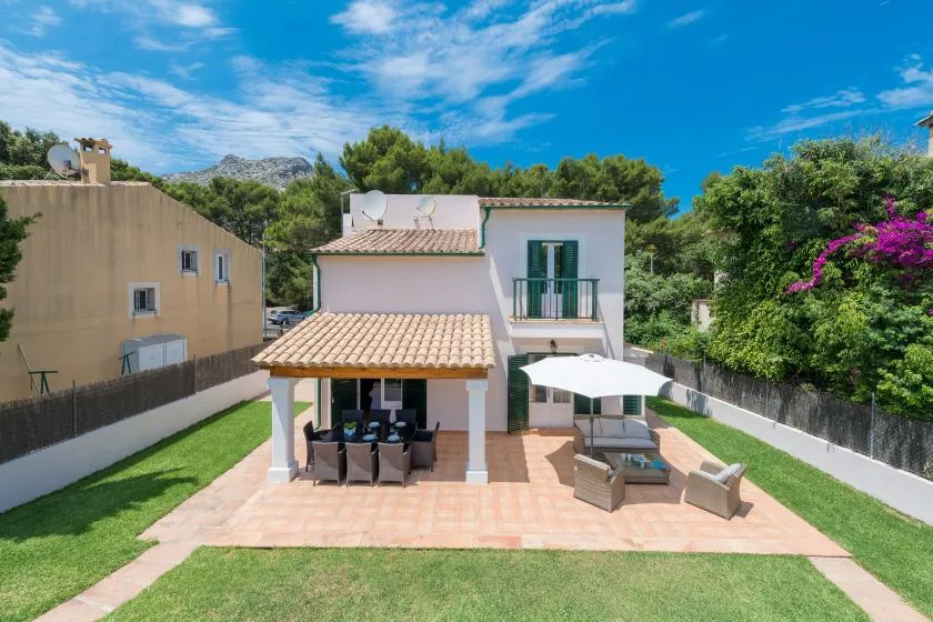 A house with a tiled patio, outdoor seating, and a white umbrella.