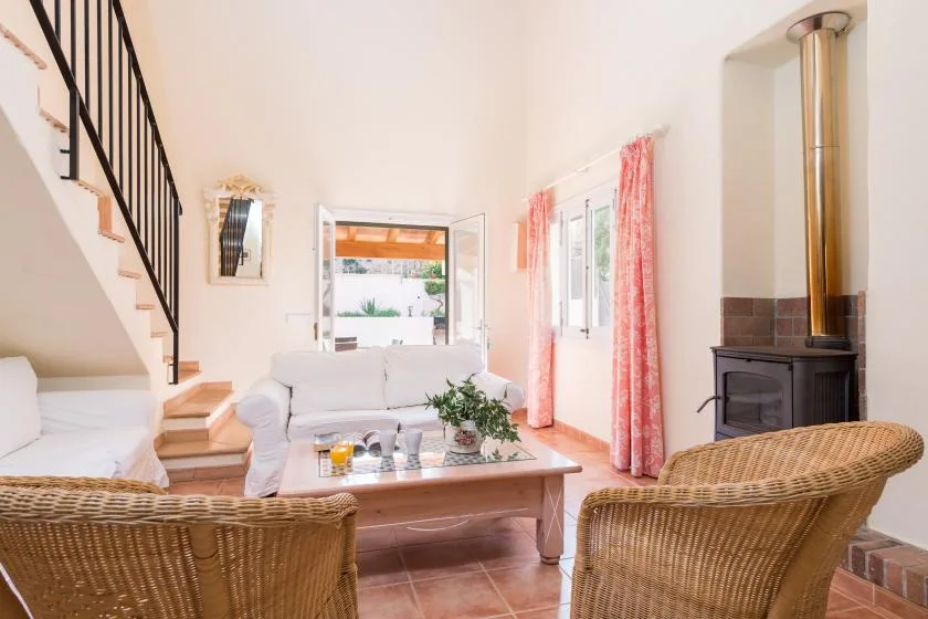 A bright living room with seating, a coffee table, and a staircase.