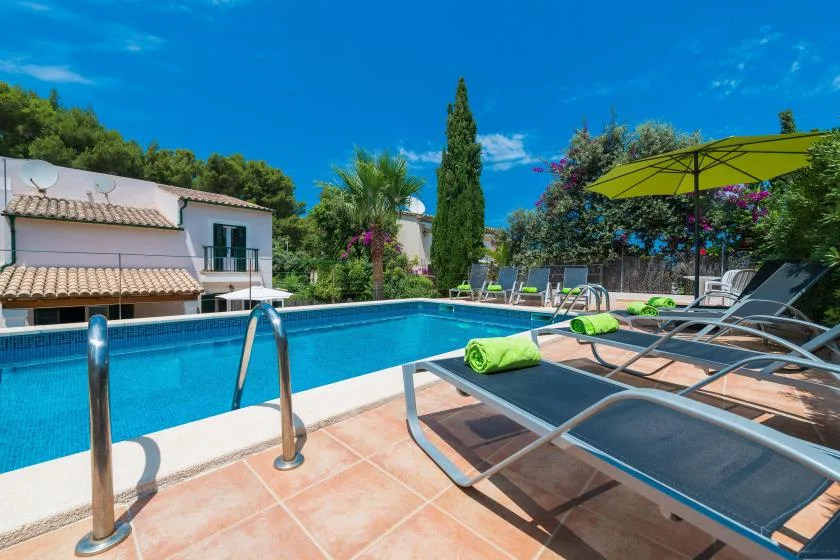 An outdoor swimming pool is bordered by lounge seating and a bright green parasol.
