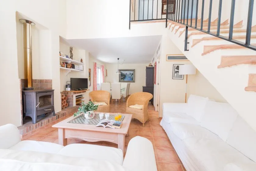 A bright living room with seating, a coffee table, and a staircase.