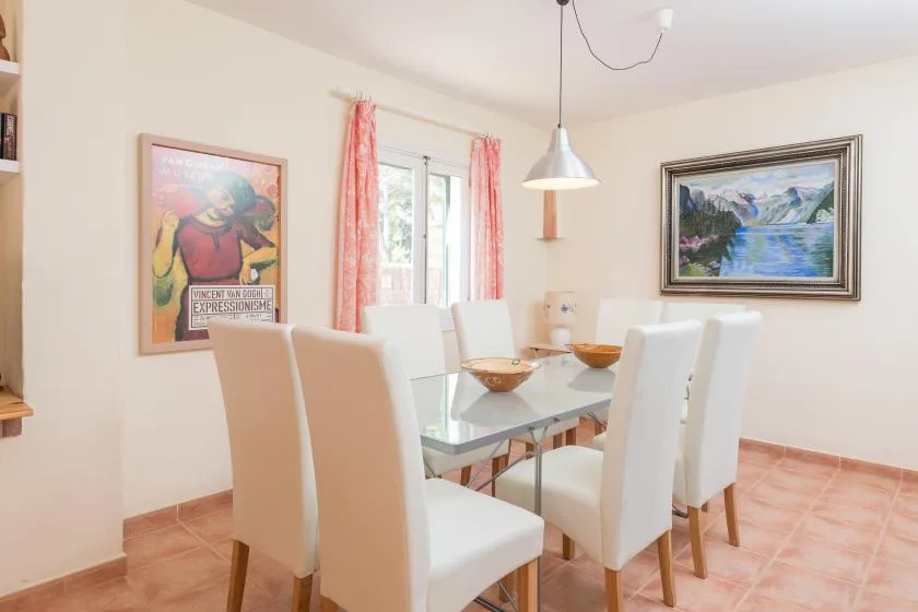 A bright dining area with a glass table and white seating.